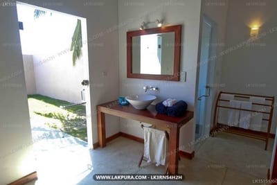 Divyaa Lagoon - bathroom with wooden vanity, mirror, and open door to garden