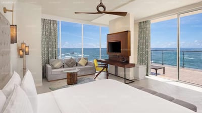 Radisson Blu Resort - spacious bedroom with ocean view and living area through glass doors