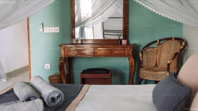 Rise - bedroom with turquoise wall, wooden dresser and wicker chair