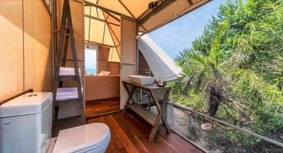 Kodev - wooden treehouse interior with toilet, desk, and forest views