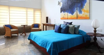 Nil by Yoho - bright bedroom with blue bedding, seating area, and abstract wall art