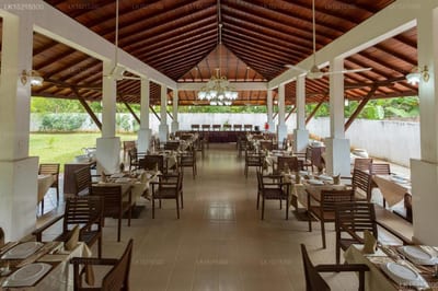Chenra Hotel, Kataragama - open-sided dining pavilion with wooden chairs and tables, green grounds visible beyond