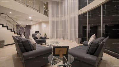 W Residenz, Kandy - modern living room with gray sofas, floor-to-ceiling windows and staircase