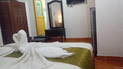 Stemyra - bedroom with double bed, green throw, white towel swan, and wooden floor