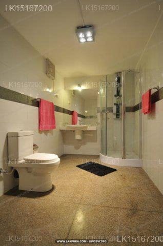 Colombo Haven - bathroom with toilet, glass shower enclosure, and red towels
