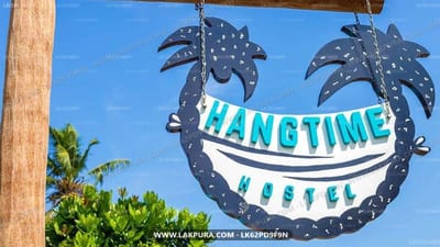 Hangtime Hostel - metal palm tree sign hanging against blue sky