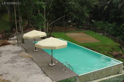 Bopath Fall Rock Chalets - turquoise swimming pool with umbrellas and forest backdrop