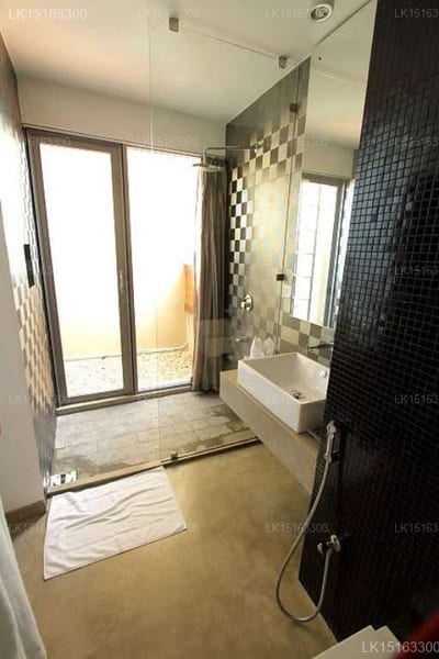 The Ocean Front - modern bathroom with glass shower, black tile wall, and balcony doors
