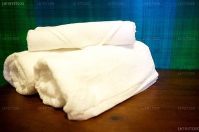 Roman Beach - rolled white towels stacked on wooden surface