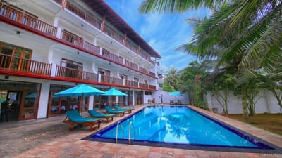 Rockside Beach Resort - rectangular pool with blue umbrellas, multi-story hotel building behind