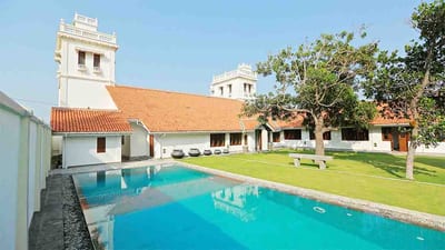 Monsoon Villa - swimming pool and manicured lawn facing whitewashed villa with towers