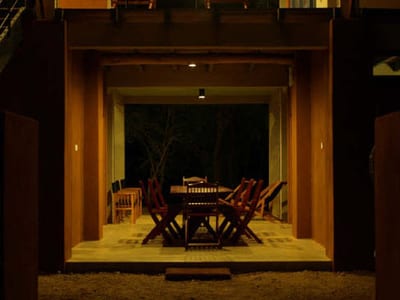 Wapi - wooden pavilion with dining table and chairs lit at night