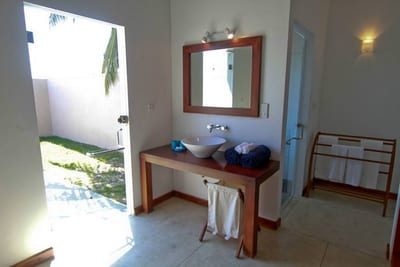 Divyaa Lagoon - bathroom with wooden vanity, mirror, and open door to garden