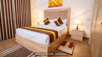 Raj Residencies, Kandy - bedroom with wooden bed, white linens, gold accents and bedside lamps